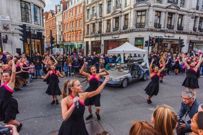 Dancers and a DeLorean car at the Regent Street Motor Show, London UK